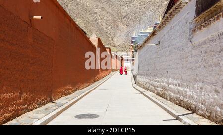 Xiahe, Provinz Gansu / China - 28. April 2017: Blick entlang einer Gasse im Labrang Kloster. In der Ferne kleideten sich zwei tibetische Mönche des Gelug-Ordens Stockfoto