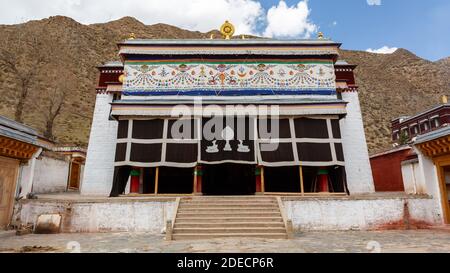 Xiahe, Provinz Gansu / China - 28. April 2017: Frontansicht des Tempelgebäudes im Labrang Kloster. Mit goldfarbenen Hirsen und Dharma-Rad am Stockfoto