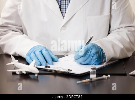 Arzthand mit Stiftfüllung in Daten, in Form, mit weißer Fläche, Spritze, Computertastatur, Auf Arbeitstisch, weißer Hintergrund. Stockfoto