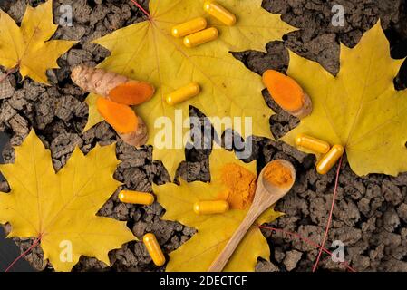 Kork flacher Hintergrund mit Kurkuma in verschiedenen Formen Kapseln und Puder in einem Mini-Holzlöffel Topf und Wurzel geschnitten In Stücke Stockfoto