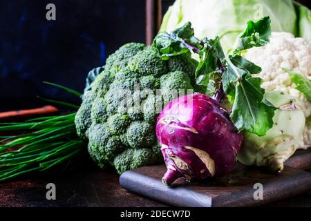 Verschiedene Arten von Kohl wie Weißkohl, Blumenkohl, Brokkoli, Kohlrabi auf dunklem Tisch, Herbsternte, selektiver Fokus Stockfoto