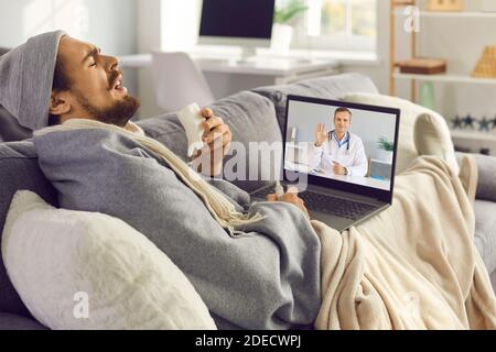 Kranker Mann hustet und niesen, während er online medizinische Beratung Mit eHealth Arzt Stockfoto