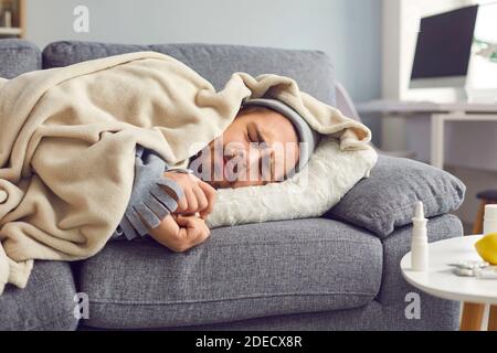 Nahaufnahme von kranken Mann mit Grippe, Fieber und Kopfschmerzen schlafen eingewickelt in karierten auf dem Sofa. Stockfoto