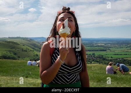 Junge Frau, die an einem Sommertag im Devils Dyke, East Sussex, Großbritannien, ein Eis isst Stockfoto