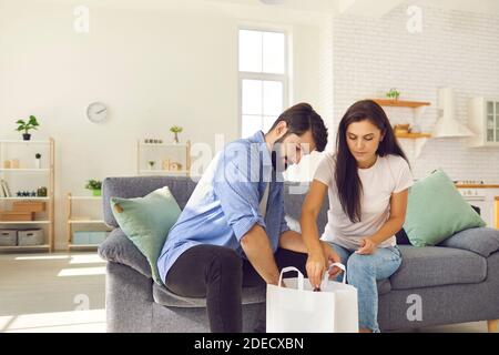 Junge Männer und Frauen packen einen weißen Beutel mit Lebensmitteln aus, die ihnen vom Lieferservice nach Hause geliefert werden. Stockfoto