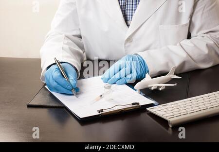 Arzthand mit Stiftfüllung in Daten, in Form, mit Impfstoff, Spritze, weiße Fläche, Computertastatur, auf Arbeitstisch, weißer Hintergrund. Stockfoto