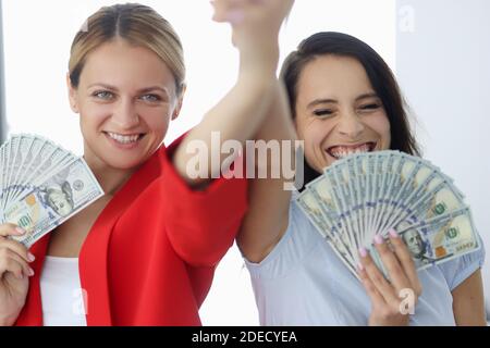 Zwei lächelnde Geschäftsfrau halten amerikanische Rechnungen. Stockfoto