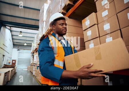 Afrikanischer Arbeiter mit Schutzhelm, der in der Industriefabrik arbeitet Stockfoto