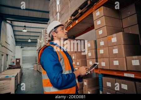 Seitenansicht eines männlichen Fabrikarbeiters mit digitalem Tablet Zur Verwaltung von Bestandsaufzeichnungen Stockfoto