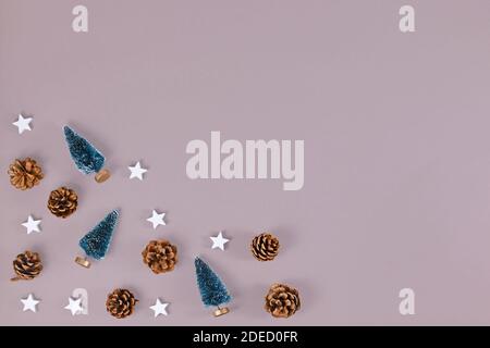 Weihnachts-Wohnung lag mit kleinen Weihnachtsbäumen, Pinienzapfen und hölzernen Sternornamenten in der Ecke von grauem Hintergrund mit leerem Kopierraum Stockfoto