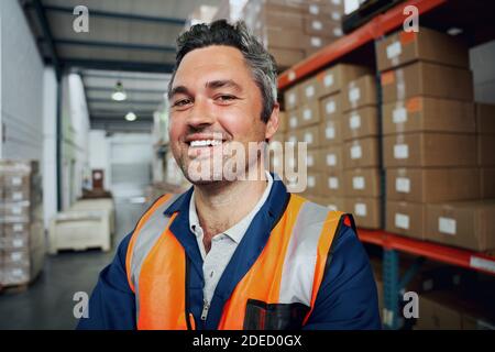 Nahaufnahme eines glücklichen Fabrikarbeiters mit industriellem Hintergrund Stockfoto