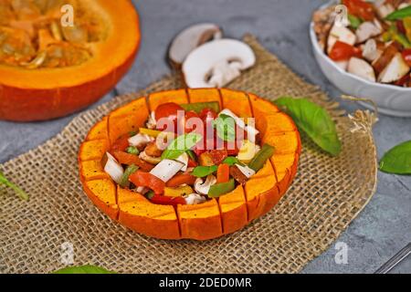 Vegan gebackenes rotes Kürbisgemüse mit Paprika, Tomaten und Pilzen, umgeben von Zutaten Stockfoto