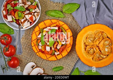 Vegan gebackenes rotes Kürbisgemüse mit Paprika, Tomaten und Pilzen, umgeben von Zutaten Stockfoto