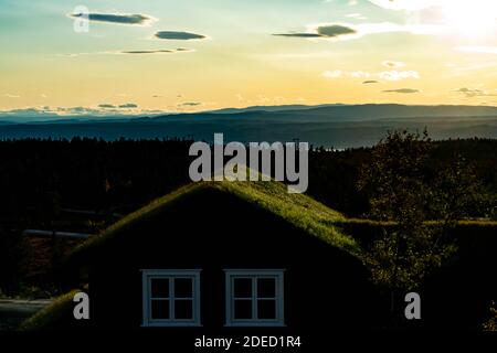Alte Hütte mit Rasendach mit Blick auf ein wunderschönes Wildnistal bei Sonnenuntergang. . Hochwertige Fotos Stockfoto