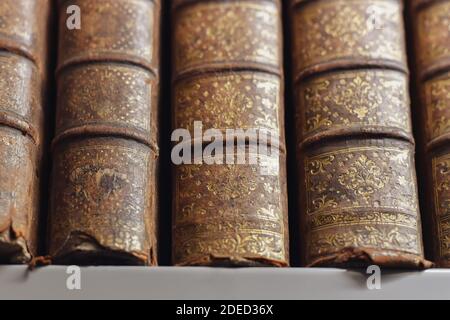 In einer Bibliothek stehen antike, vergoldete Bücher auf Regalen Stockfoto