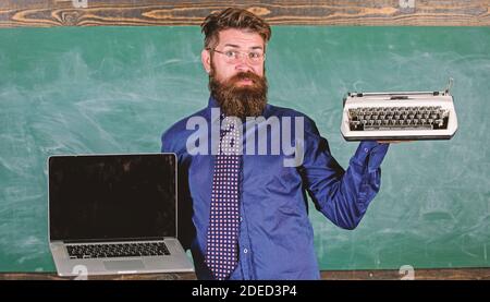 Wählen Sie die richtige Lehrmethode. Lehrer wählt Lehransatz. Digital gegen Retro. Moderne Technologien profitieren. Modern statt veraltet. Lehrer bärtige Hipster hält Schreibmaschine und Laptop. Stockfoto