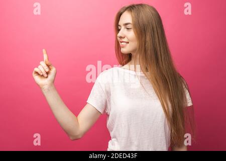 Nahaufnahme Porträt der glücklichen blonden Frau zeigt den Vorderfinger zur Seite, steht auf einem rosa Hintergrund, zeigt etwas in leeren Kopieplatz für adv Stockfoto