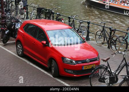 AMSTERDAM, NIEDERLANDE - 10. JULI 2017: Rotes Volkswagen Polo Cross kleines Stadtauto geparkt am Kanal in Amsterdam. Die Niederlande haben 528 zugelassene Autos Stockfoto