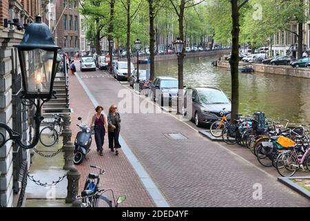 AMSTERDAM, NIEDERLANDE - 10. JULI 2017: Menschen wandern entlang des Herengracht-Kanals in Amsterdam, Niederlande. Amsterdam ist die Hauptstadt der Niederlande Stockfoto