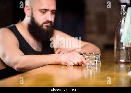Hipster brutalen Mann, Alkohol zu trinken bestellen mehr Getränke an der Theke. Alkoholismus und Depression. Kerl verbringen Freizeit in bar mit Alkohol. Mann betrunken sitzen alleine in eine Kneipe. Alkohol Konzept süchtig. Stockfoto