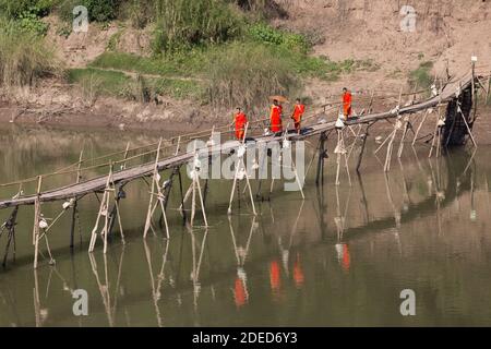 Luang Prabang Laos 12.23.2017 buddhistische Mönche überqueren Fluss durch alte Holzbrücke Stockfoto