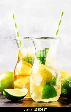 Eisschwarzer und grüner Tee mit Zitrone, Limette und Eis in der Kanne, selektiver Fokus Stockfoto