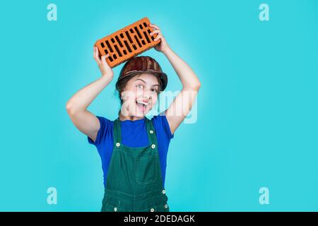 Fröhliche Kinderarbeiter mit Gebäude Uniform und Ziegel, Gebäude. Stockfoto