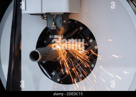 Laserschneidmaschine arbeitet mit zylindrischem Metallwerkstück mit Funken Stockfoto