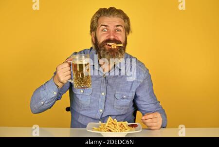 Pommes Frites Kartoffel. Kerl in der amerikanischen Bar Bier Glas trinken und essen Kartoffel. Cheers. Fußball im Fernsehen. american Fast Food. Glücklich bärtigen Mann mit Bier und pommes frites. Stockfoto