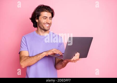 Portrait von schönen Mann Look verwenden Netbook positive Programmierer tragen Violett isoliert auf rosa Hintergrund Stockfoto