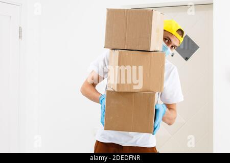 Lieferung Mann hält Pappkartons in medizinischen Gummihandschuhe und Maske. Copy-Raum. Schnelle und kostenlose Lieferung Transport . Online-Shopping und Express Stockfoto