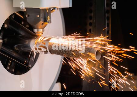 Laserschneidmaschine arbeitet mit zylindrischem Metallwerkstück mit Funken Stockfoto