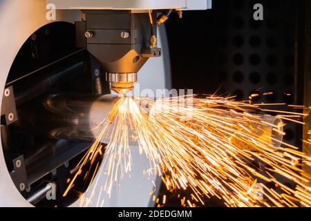 Laserschneidmaschine arbeitet mit zylindrischem Metallwerkstück mit Funken Stockfoto