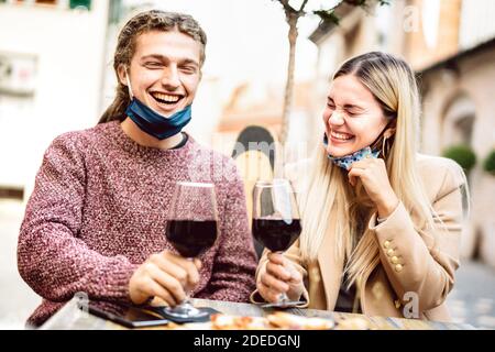 Junges Paar in der Liebe mit offenen Gesichtsmasken Spaß haben In der Weinbar im Freien - Glückliche Jahrtausendeliebhaber genießen das Mittagessen Gemeinsam auf der Restaurantterrasse Stockfoto
