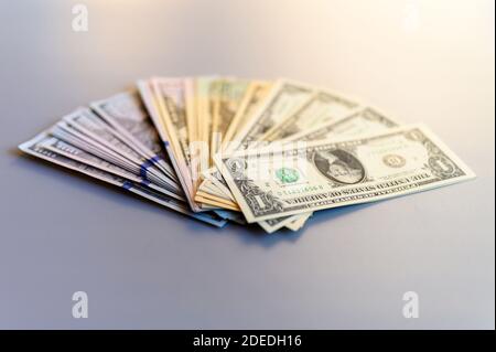 Haufen Geld Fan auf einem grauen Hintergrund. Amerikanische Dollar-Scheine von verschiedenen Stückelungen verteilt in einem fanned Stockfoto