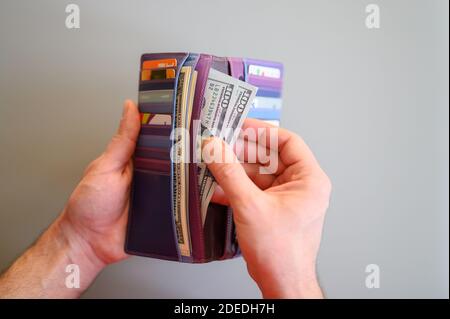 Herren Hände halten 100 Dollar Scheine und eine Brieftasche auf Ein grauer Hintergrund Stockfoto