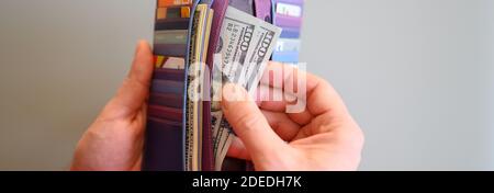 Herren Hände halten 100 Dollar Scheine und eine Brieftasche auf einem grauen Hintergrund. Banner Stockfoto