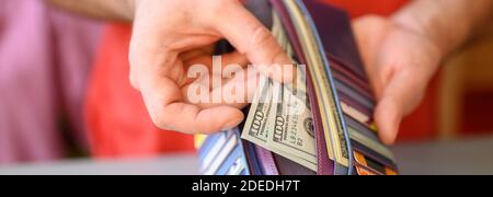 Herrenhände halten 100 Dollar Scheine und eine Brieftasche auf einem grauen Tisch. Banner Stockfoto