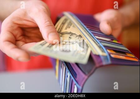 Herren Hände halten 20 Dollar Scheine und eine Brieftasche auf Ein grauer Tisch Stockfoto
