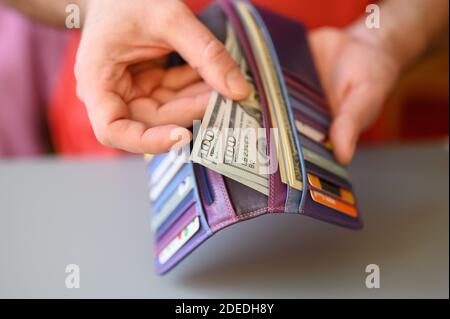 Herren Hände halten 100 Dollar Scheine und eine Brieftasche auf Ein grauer Tisch Stockfoto