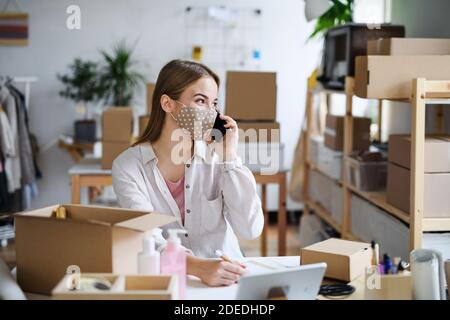 Junge Frau dropshipper mit Smartphone zu Hause arbeiten, Coronavirus Konzept. Stockfoto