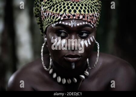 Afrikanische Frau sitzt im Aburi Wald in Ghana mit Weiße Malerei auf ihrem Gesicht und Kopfschmuck Stockfoto