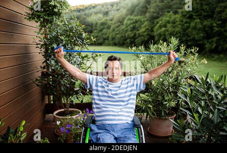 Älterer Mann im Rollstuhl, der auf der Terrasse trainieren kann. Stockfoto