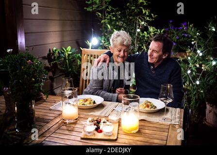 Ein älteres Paar im Rollstuhl, das abends auf der Terrasse zu Abend gegessen hat und sich gut Vergnügen konnte. Stockfoto