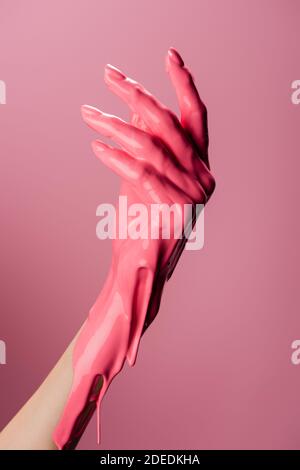 Beschnittene Ansicht der Hand mit tropfender Farbe isoliert auf rosa Stockfoto