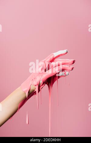 Beschnittene Ansicht der Hand mit tropfender Farbe isoliert auf rosa Stockfoto