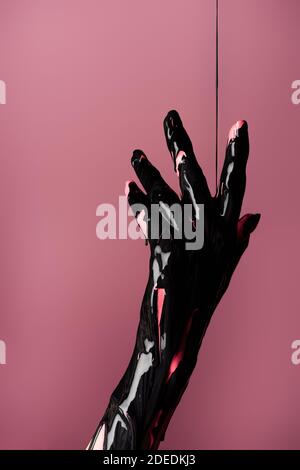 Teilansicht der Hand mit abgetropfter schwarzer Farbe isoliert Rosa Stockfoto