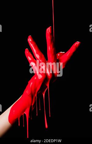 Teilansicht der bemalten Hand mit roter tropfender Farbe isoliert Auf Schwarz Stockfoto