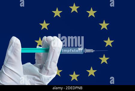 Eine Hand hält eine Spritze mit der deutschen Aufschrift Impfstoff Symbolisch vor einer europäischen Flagge Stockfoto