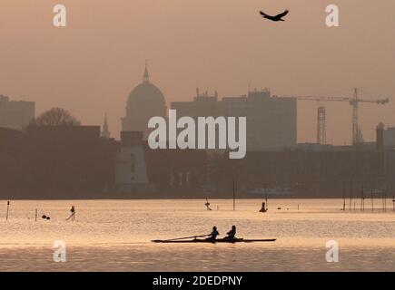 Potsdam, Deutschland. November 2020. Am späten Nachmittag rudern zwei Sportlerinnen im Wasser des tiefen Sees, durch den die Havel fließt. Im Hintergrund ist die Silhouette des Stadtzentrums mit der Kirche St. Nikolai zu sehen. Quelle: Soeren Stache/dpa-Zentralbild/ZB/dpa/Alamy Live News Stockfoto